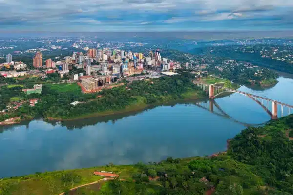 Vista aérea de una ciudad de Paraguay junto a un río, puente, edificios y áreas verdes
