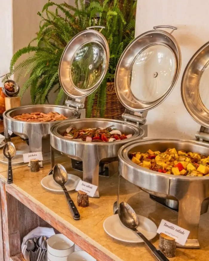 El buffet combina opciones calientes con otros alimentos presentados en recipientes individuales, facilitando que cada huésped pueda servirse según sus preferencias.