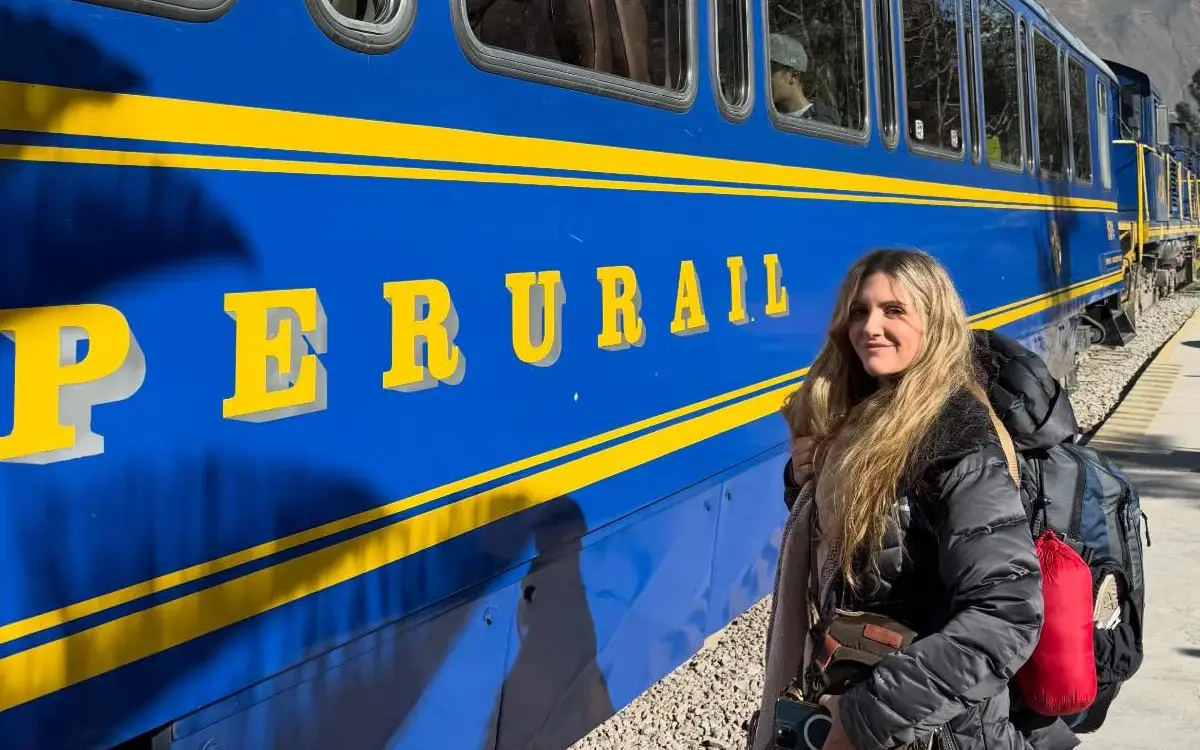 La viajera se encuentra en el andén junto al tren, una escena típica de los trayectos turísticos que conectan distintos puntos del sur del Perú.