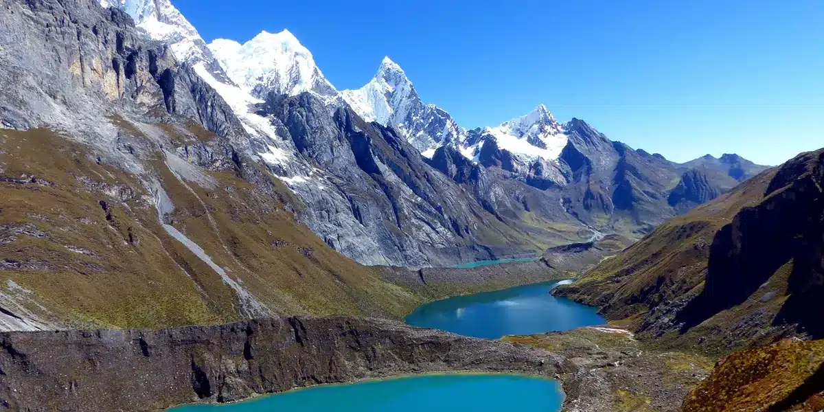 Laguna altoandina en la Cordillera Huayhuash rodeada de nevados y montañas, paisaje ideal para trekking.