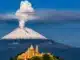 Volcán Popocatépetl: 10 datos clave, zonas permitidas y por qué no subir Volcán Popocatépetl con fumarola visible y templo antiguo rodeado de árboles verdes en primer plano.