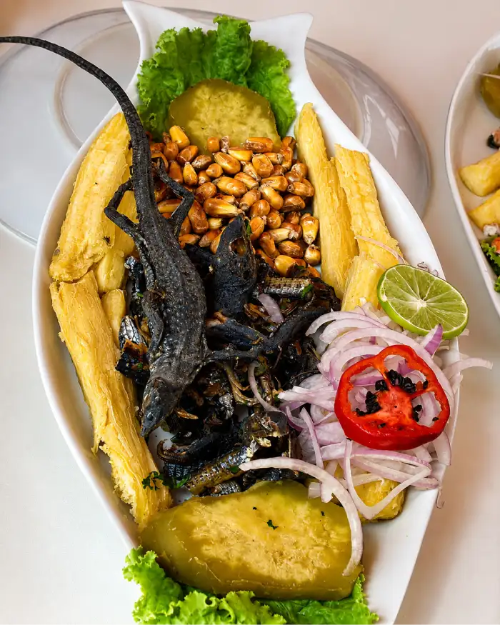 Ceviche de cañán entero servido con yuca, camote, maíz tostado, cebolla, limón y lechuga.