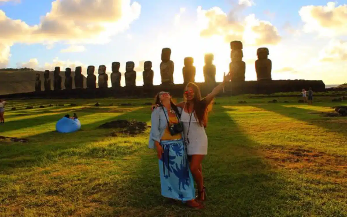 Dos turistas en la Isla de Pascua disfrutando el amanecer frente a los moáis,