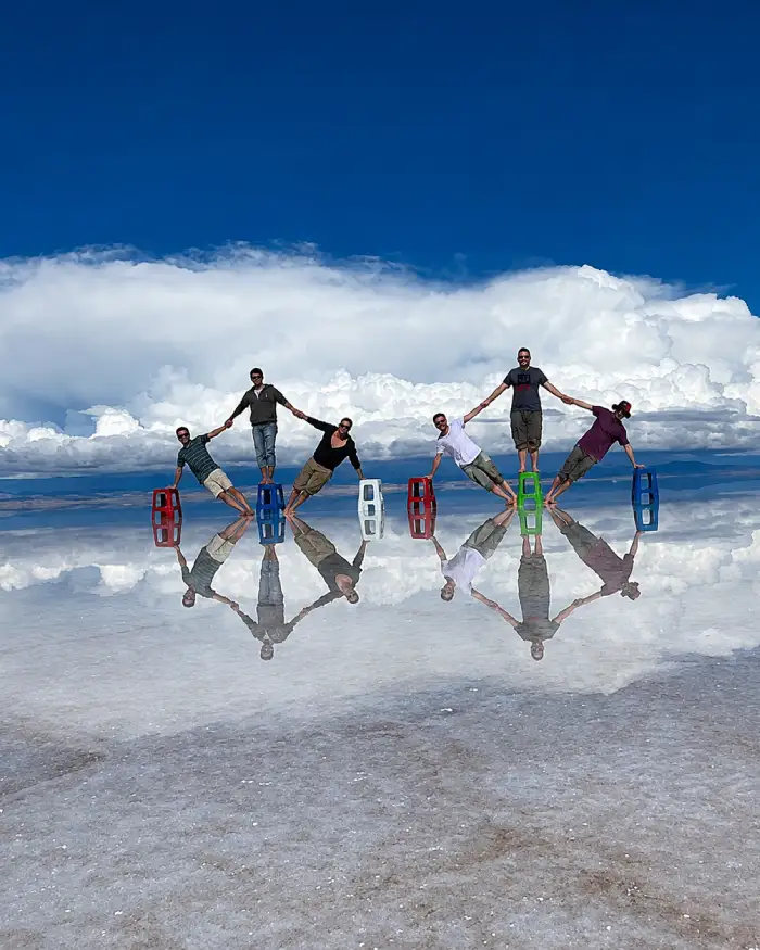 Grupo de amigos haciendo una figura con efecto espejo sobre el Salar de Uyuni