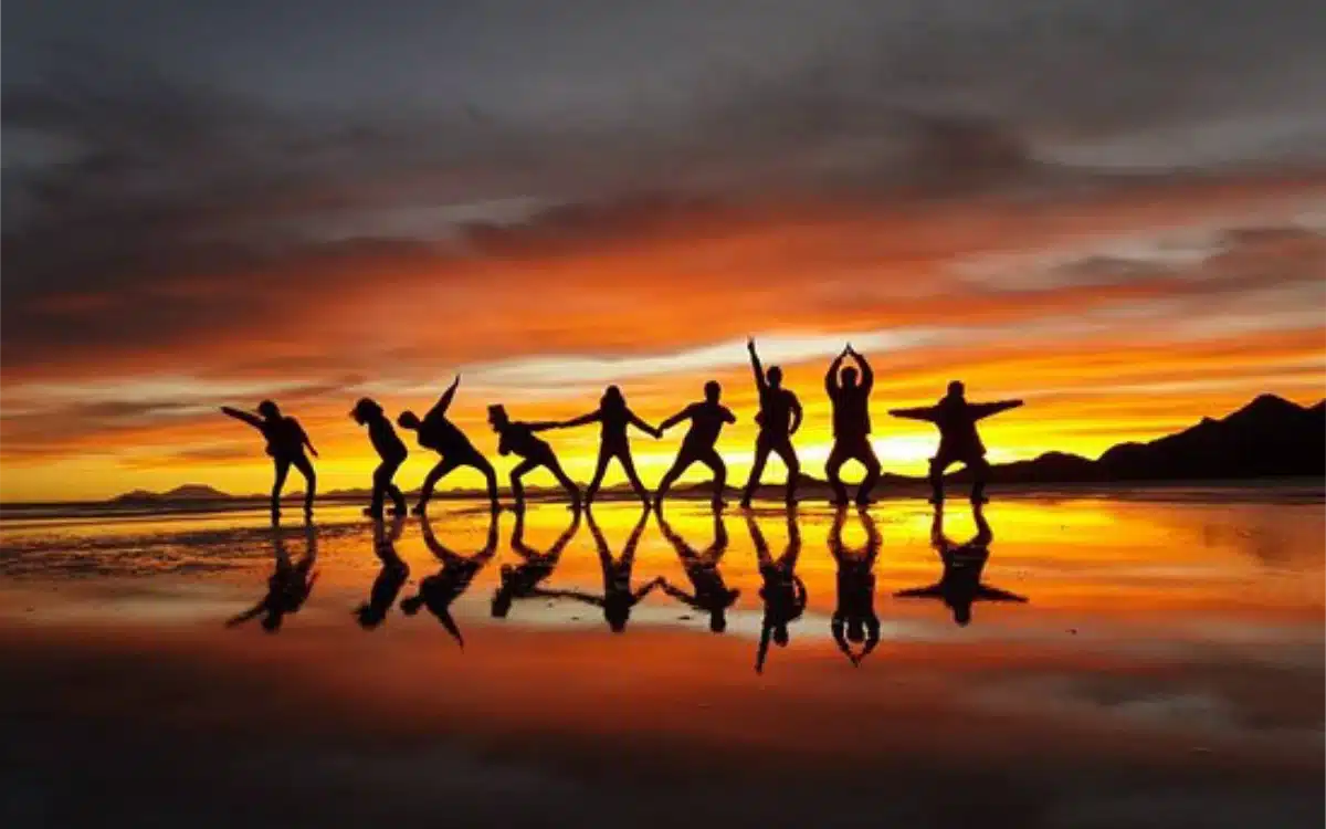 Grupo de amigos jugando con sus reflejos en el Salar de Uyuni durante el atardecer