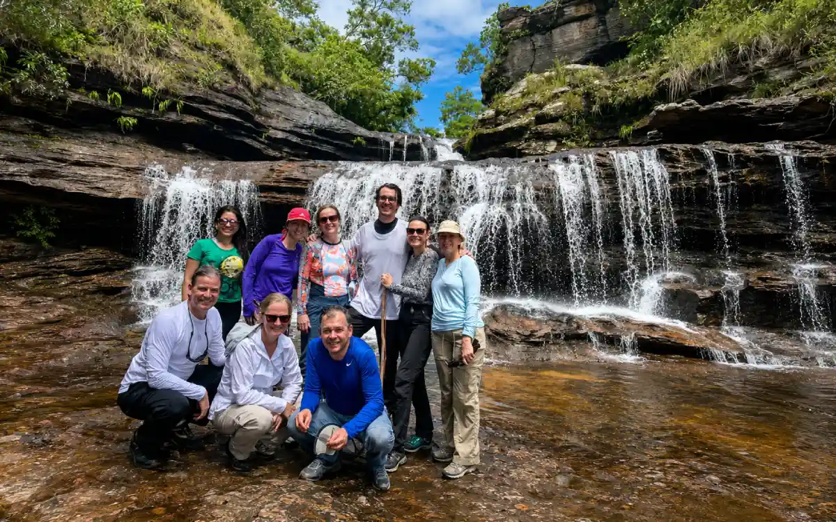 Viajeros recorriendo el sendero Salto del Águila entre rocas y cascadas de Caño Cristales