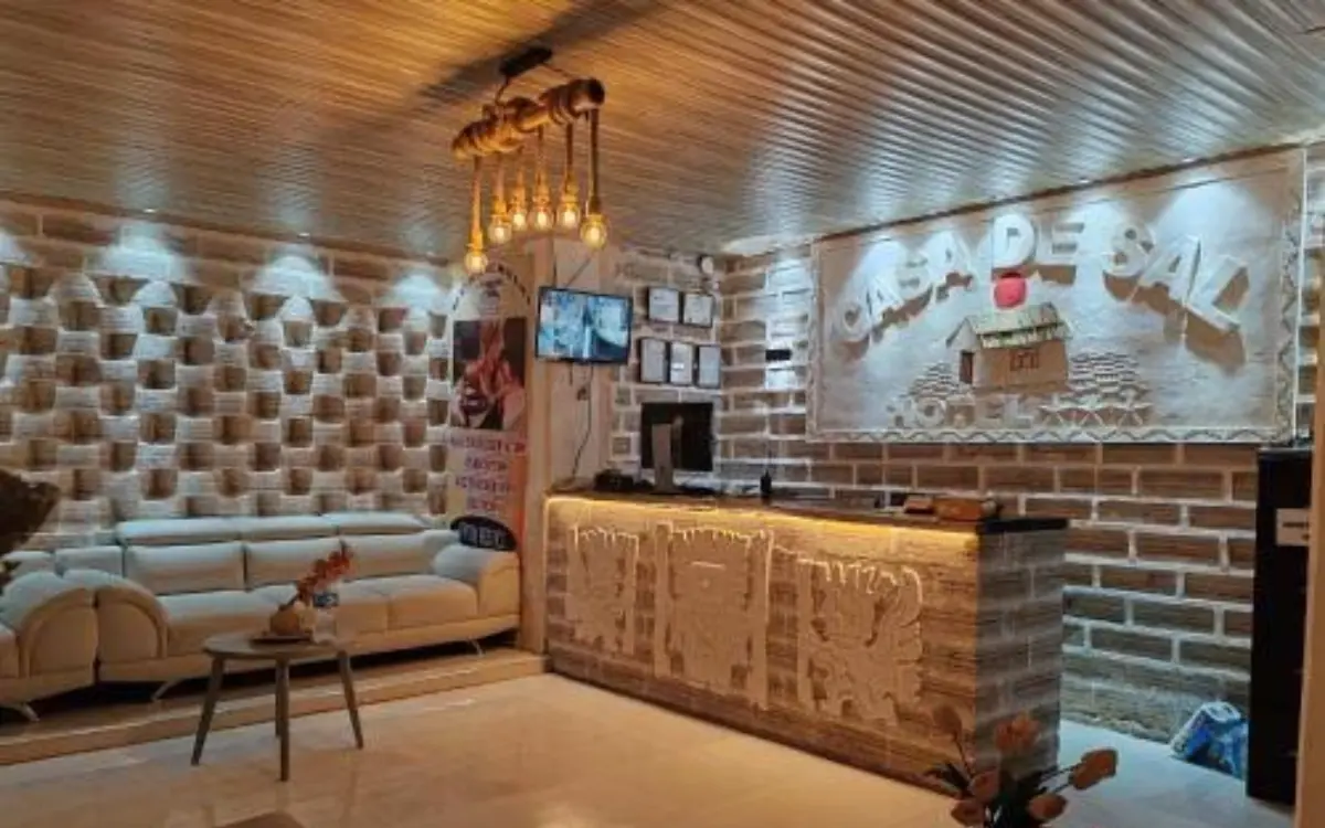 Recepción del hotel Casa de Sal en Uyuni con muros de sal, mostrador iluminado y ambiente rústico acogedor.