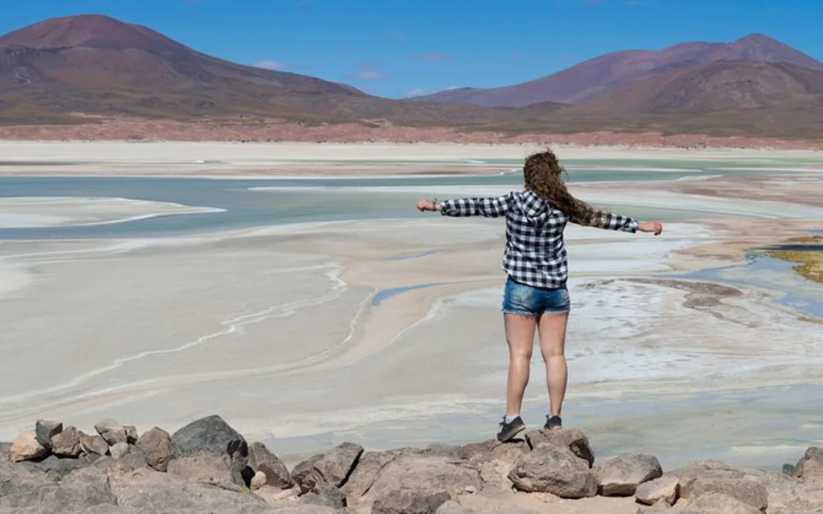 Viajera observando lagunas salinas y montañas dentro del paisaje del Salar de Atacama