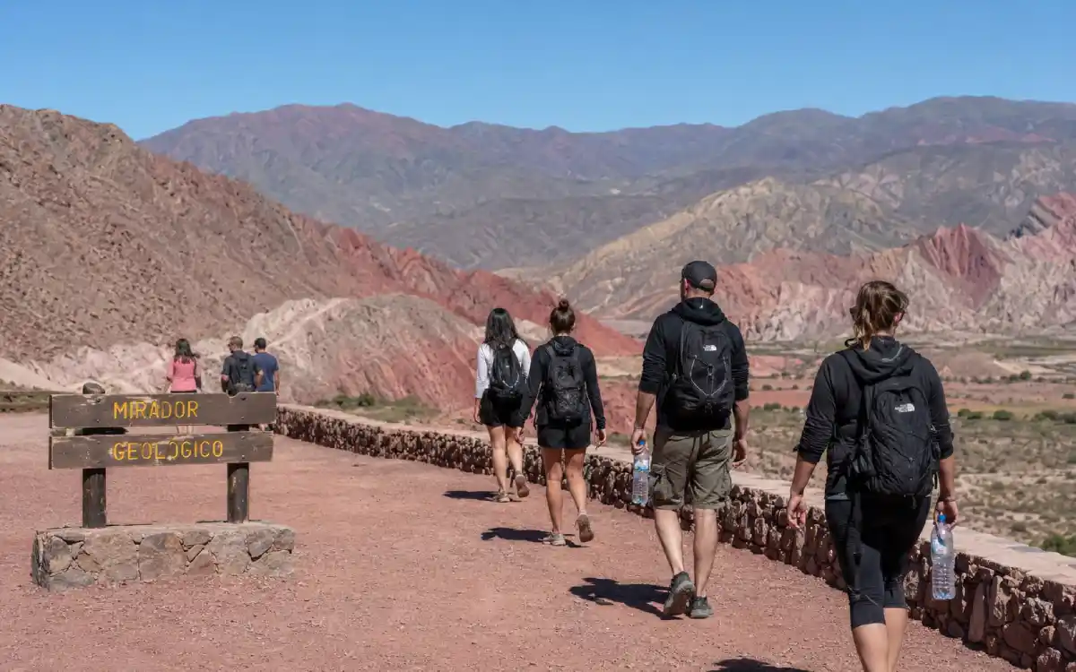 Viajeros caminando por un mirador en Quebrada de Humahuaca con botellas de agua