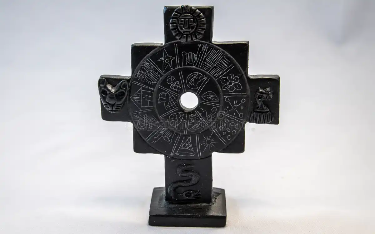 Representación decorativa de una chakana andina negra con diferentes símbolos grabados en su superficie