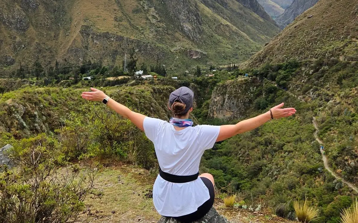 La caminante se detiene para disfrutar del silencio y la escala del paisaje antes de continuar por el sendero.