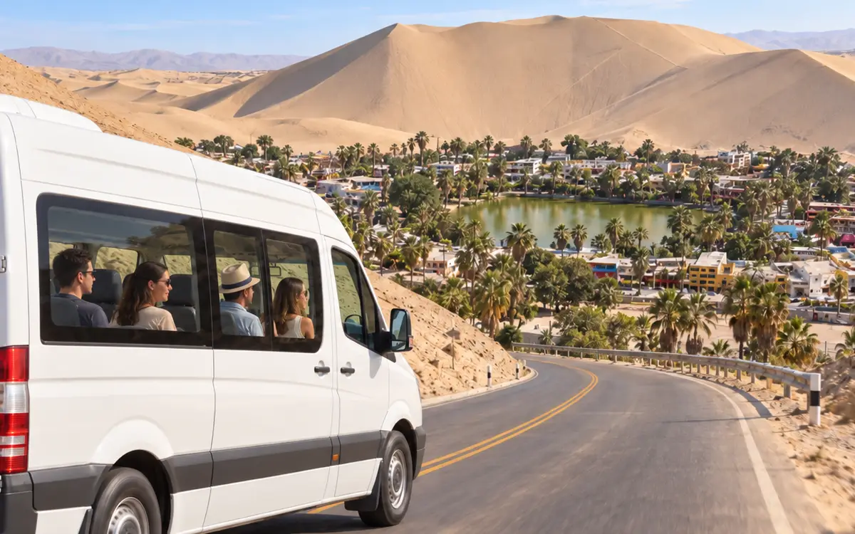 El minibús desciende por una carretera sinuosa con la laguna, las palmeras y las construcciones de Huacachina visibles al fondo.