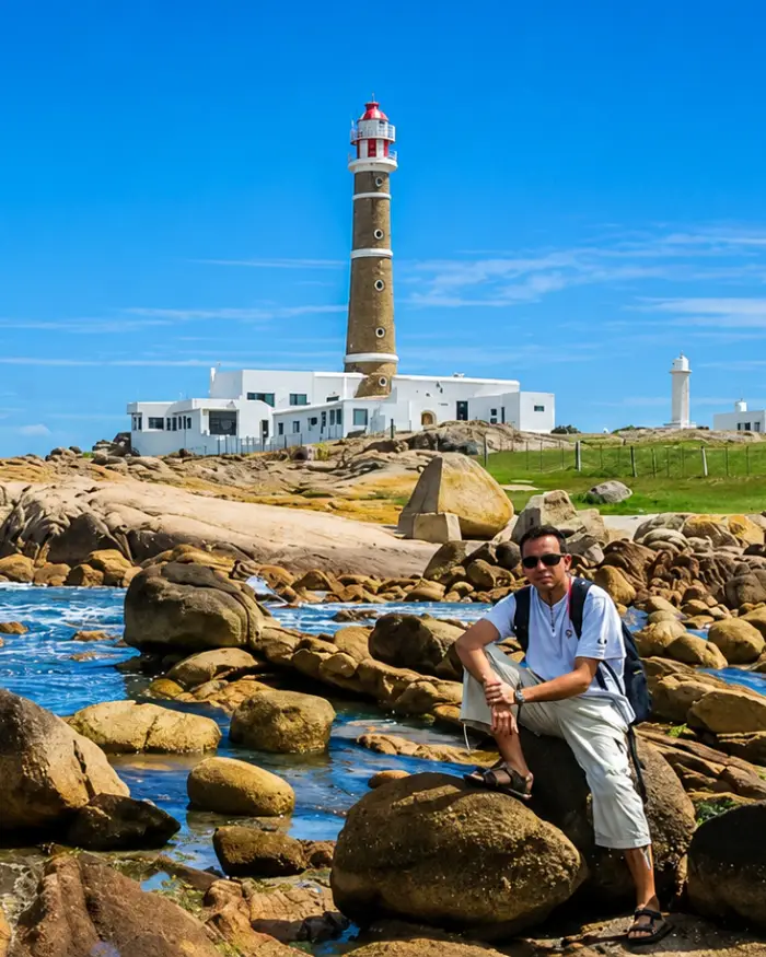Viajero en Cabo Polonio frente a la costa con el faro y construcciones del poblado