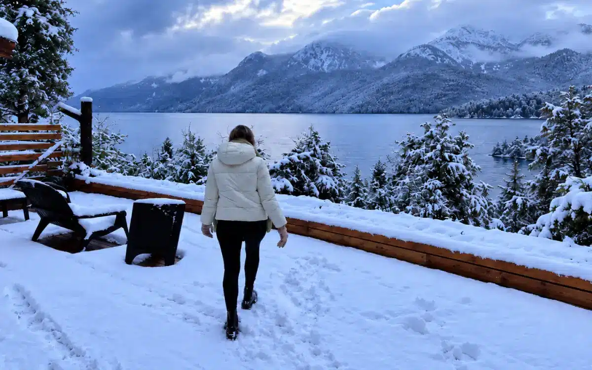 Viajera junto a una cabaña nevada en Villa Traful durante el invierno patagónico