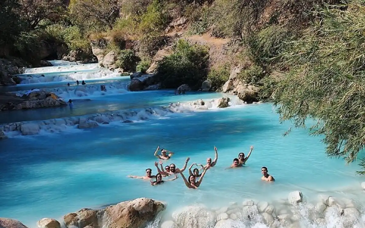 Familia y visitantes disfrutando de las aguas turquesas de las Grutas de Tolantongo