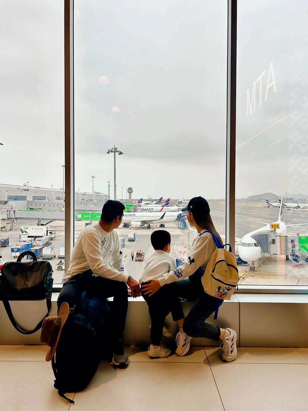 Family watching aircraft from inside the new Jorge Chávez Airport terminal