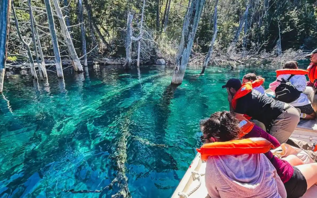 Viajeros navegando sobre el bosque sumergido del Lago Traful con chalecos salvavidas