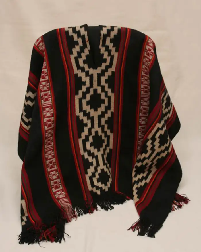 Poncho andino negro, rojo y beige decorado con patrones geométricos inspirados en la chakana