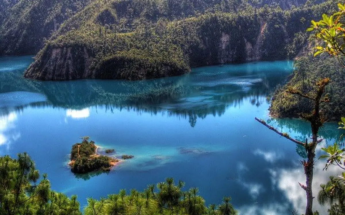 Lago Pojoj con aguas azules rodeadas por bosque en Montebello
