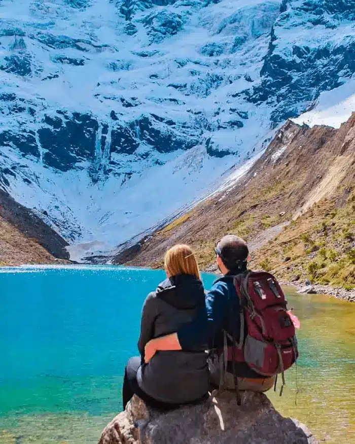 Pareja frente a la Laguna Humantay durante un día despejado de temporada seca