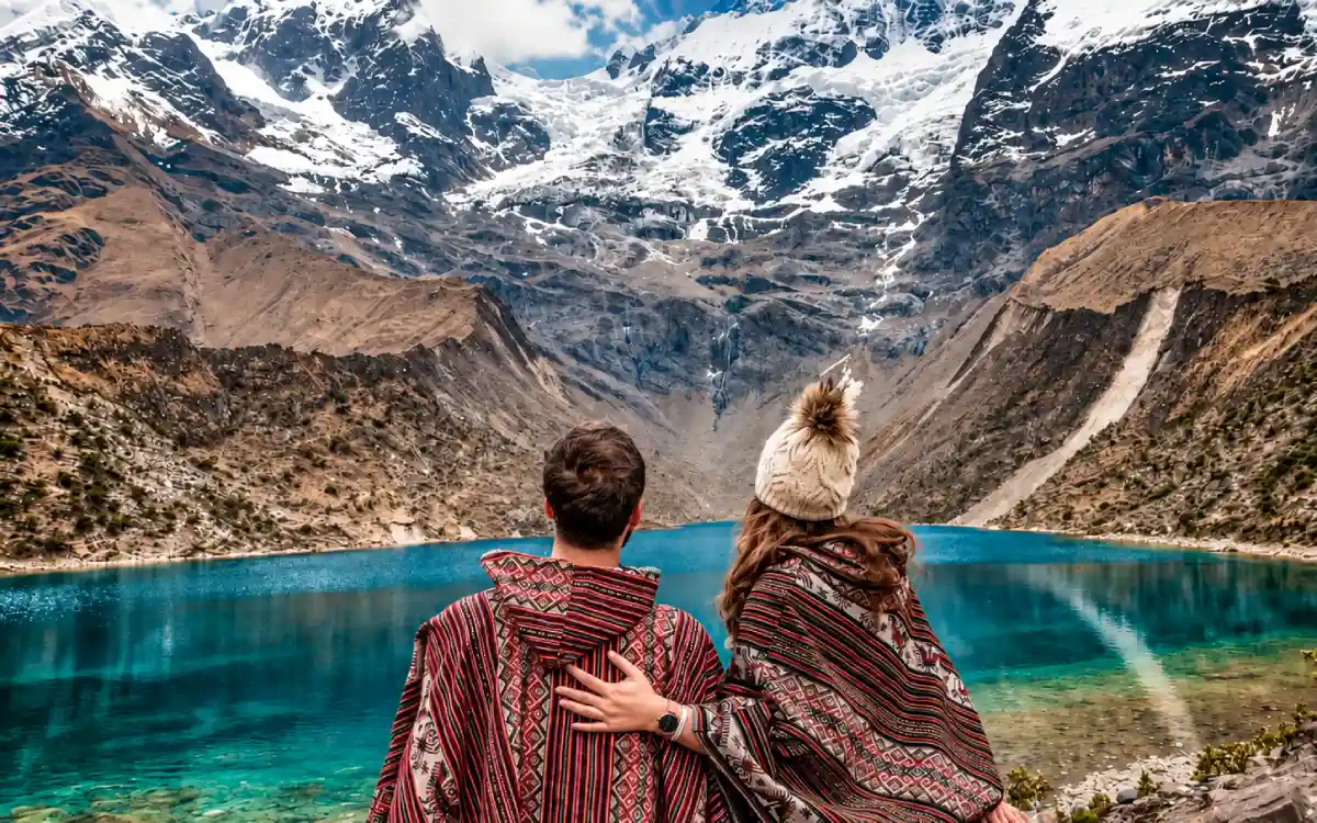 Pareja con ponchos tradicionales frente a la Laguna Humantay y el nevado de Cusco