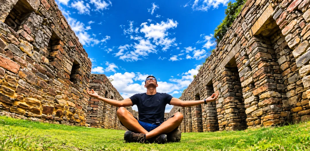 Traveler resting among stone structures at Choquequirao beneath a clear Andean sky