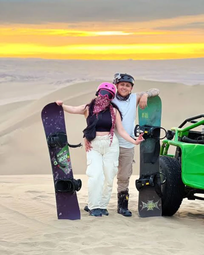 Viajeros con tablas de sandboarding junto a un buggy en las dunas de Huacachina