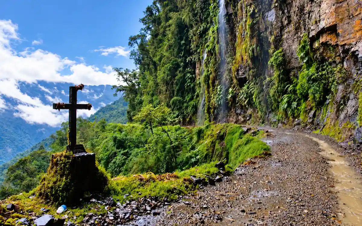 Ruta de la Muerte en Bolivia, con una cruz junto al camino estrecho