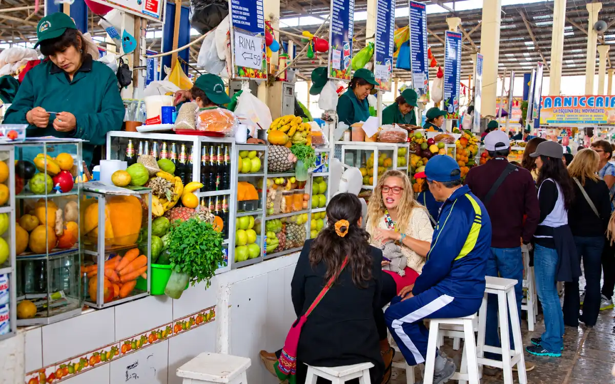 Comerciantes preparando jugos naturales y atendiendo a turistas en el Mercado de San Pedro de Cusco