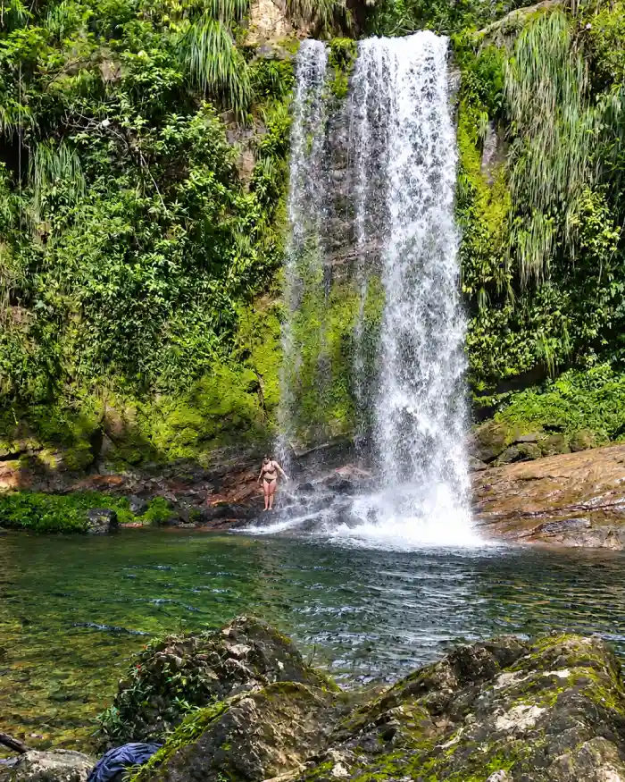 Viajera junto a una cascada rodeada por vegetación en el Parque Nacional Amboró