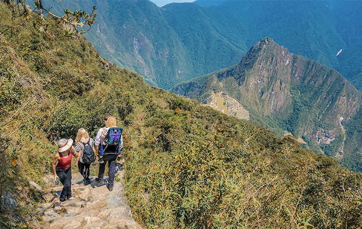 Viajantes no caminho de pedra com vistas para Machu Picchu